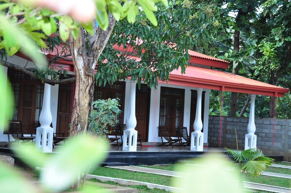 A traditional building with a red roof, white columns, and wooden doors.