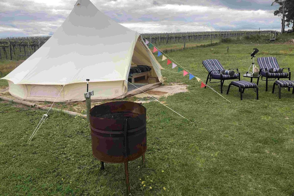Una carpa con un letrero con el número 43, una parrilla y sillas a rayas en un área verde.