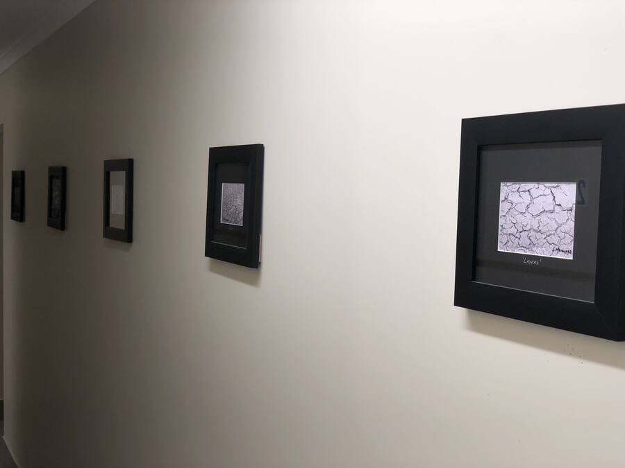 Una pared galería con obras de arte enmarcadas.