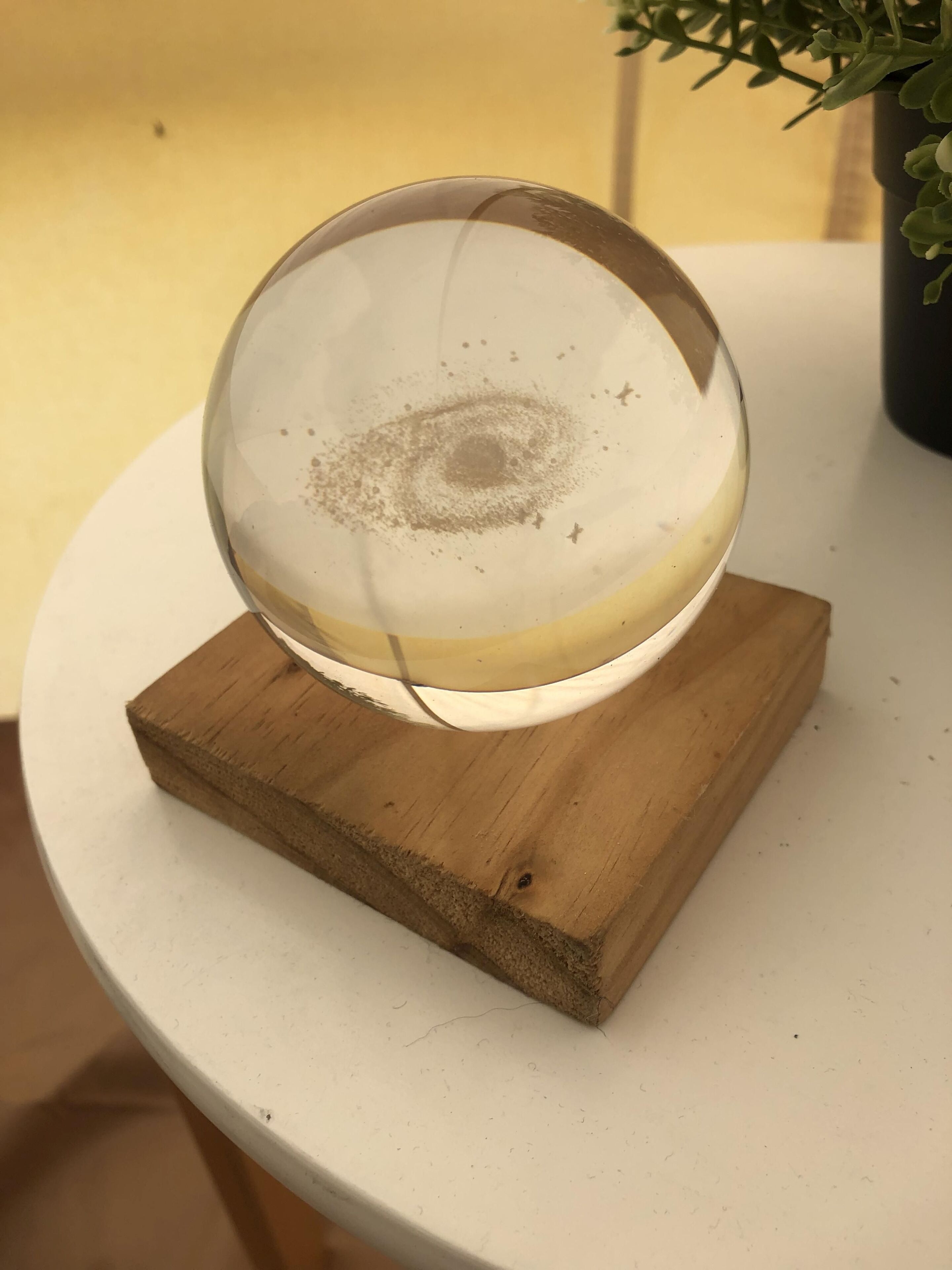 A clear glass sphere on a wooden stand.