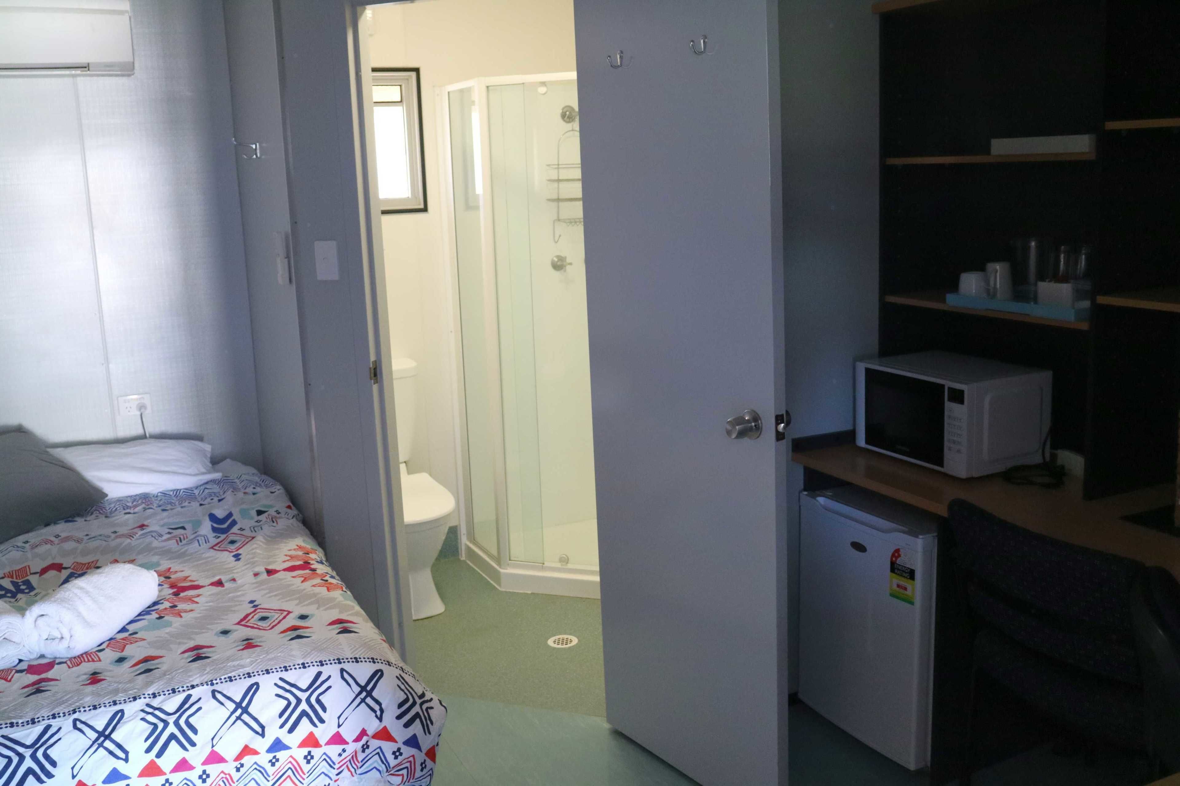Une chambre comprenant un lit, un petit réfrigérateur, un four à micro-ondes et un espace douche.