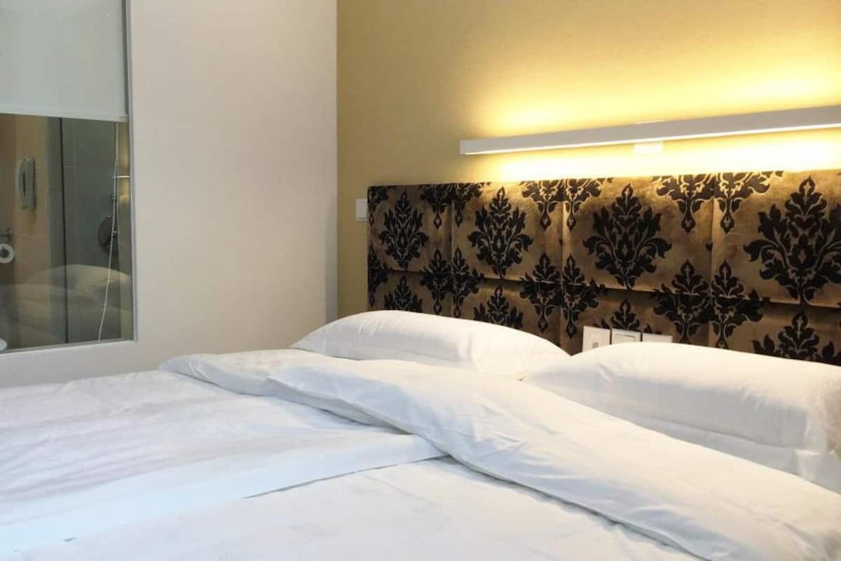 A hotel room with a bed, a large window, and a headboard with a patterned design.
