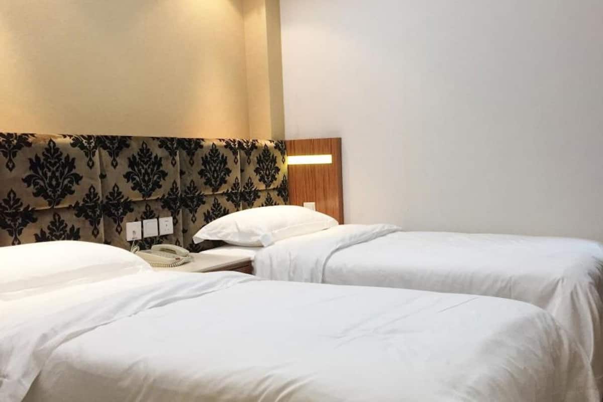 A hotel room with two single beds, a bedside telephone, and a patterned headboard.