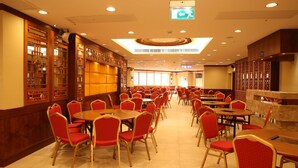 A spacious restaurant with multiple tables and chairs, a high ceiling with recessed lighting, and a traditional wooden decor. - Grand Harbour Hotel (Macau)