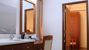 A hotel bathroom with a large mirror, a sink, and a chair. - Grand Harbour Hotel (Macau)