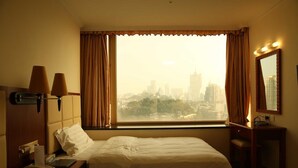 A hotel room with two beds, a desk, a chair, a telephone, and a window with curtains. - Grand Harbour Hotel (Macau)