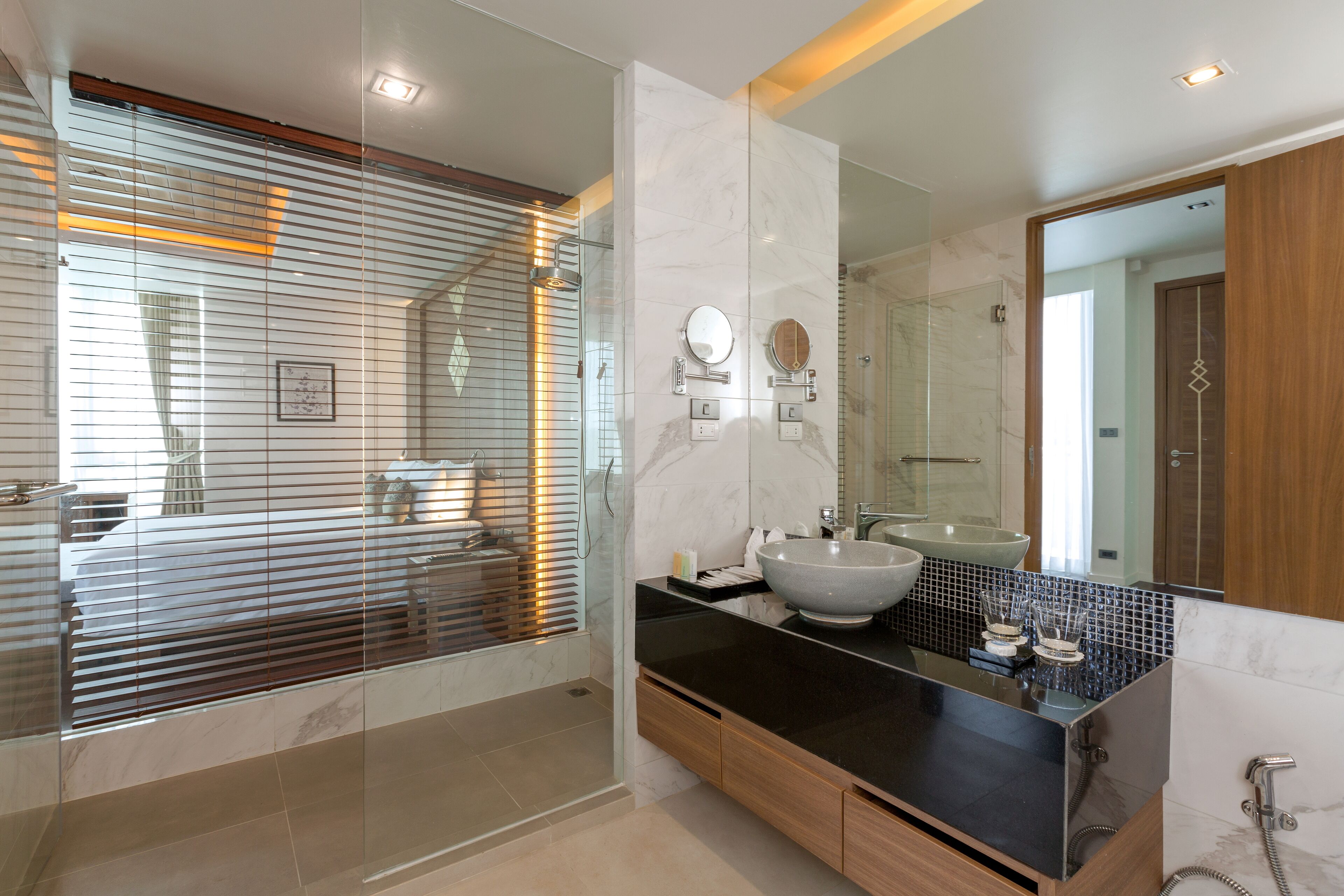 A modern bathroom with a large mirror, a vessel sink, and a walk-in shower.