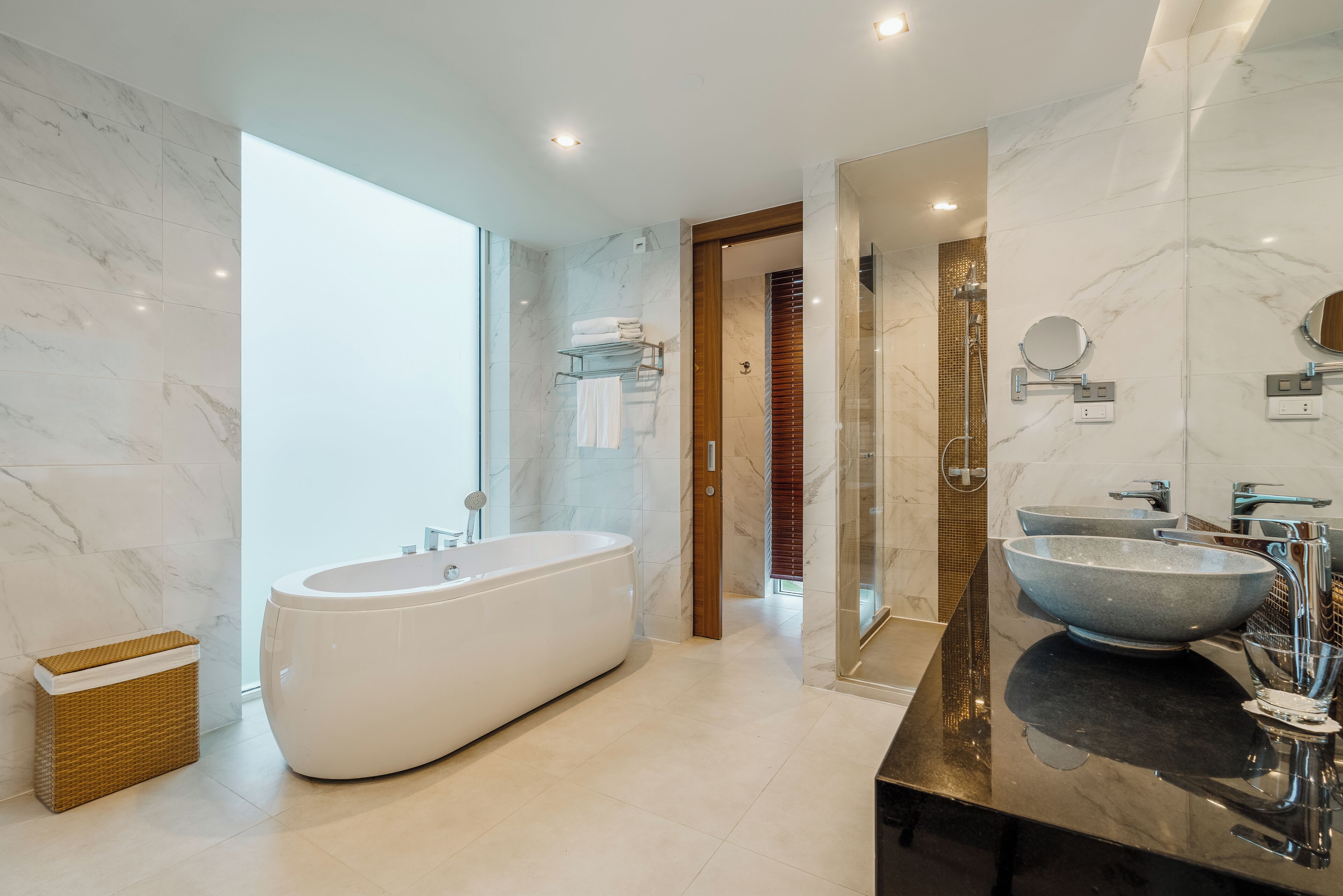 A modern bathroom with a freestanding bathtub, a double sink with a large bowl, and a glass-enclosed shower area.