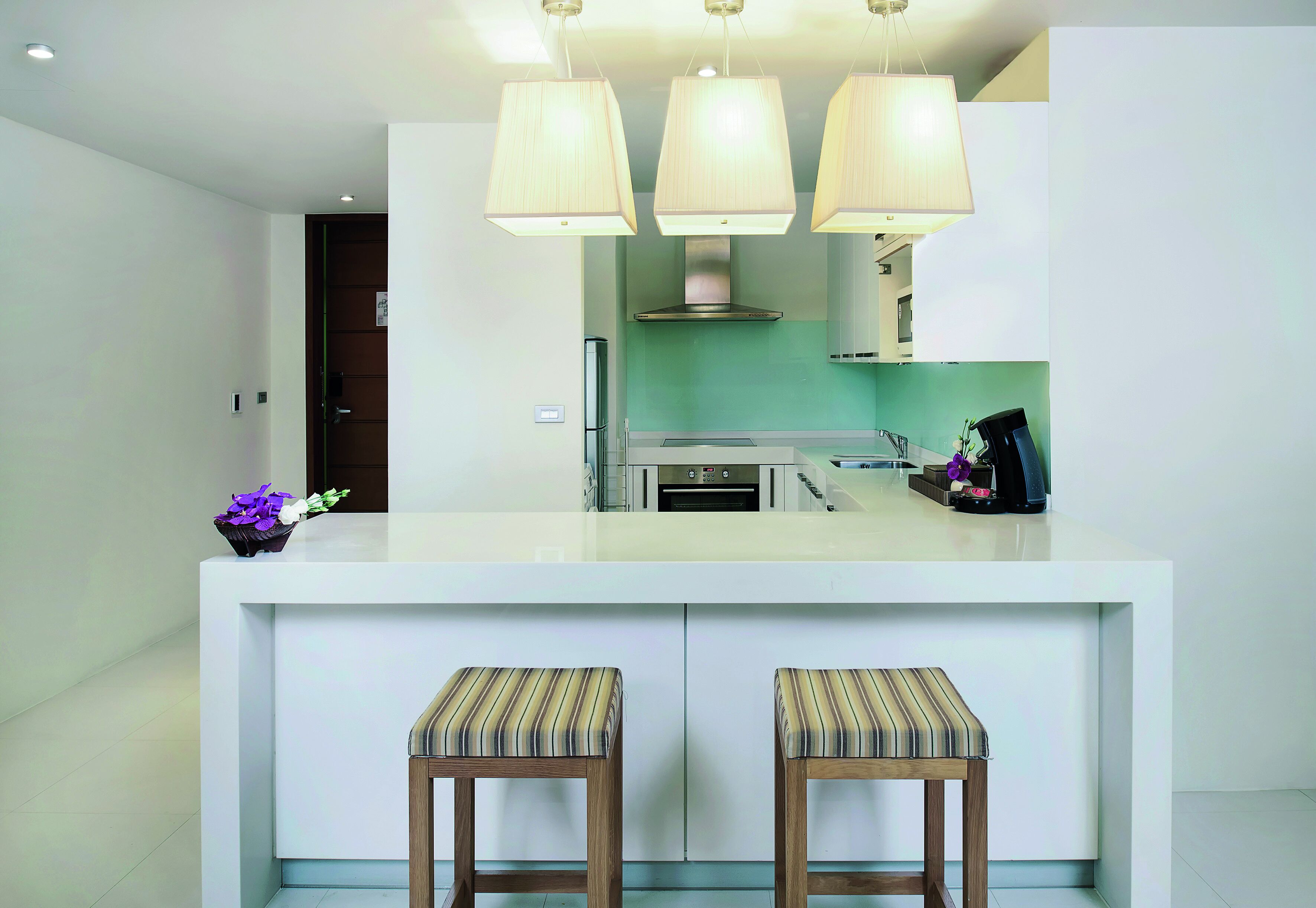 A modern kitchen with a central island, two bar stools, and pendant lighting.