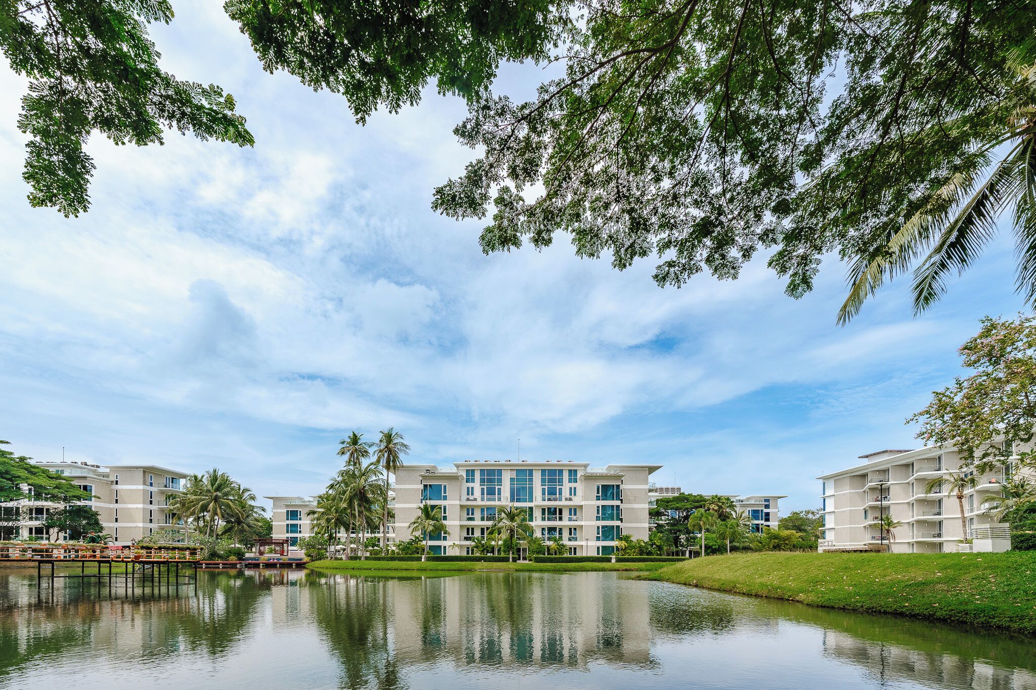 A modern hotel with multiple floors, a central courtyard, and a reflective water body.