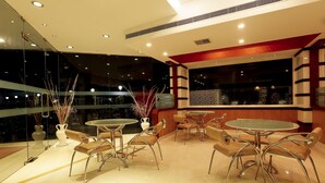 Un comedor moderno con paredes de vidrio, sillas de metal y una mesa redonda.
