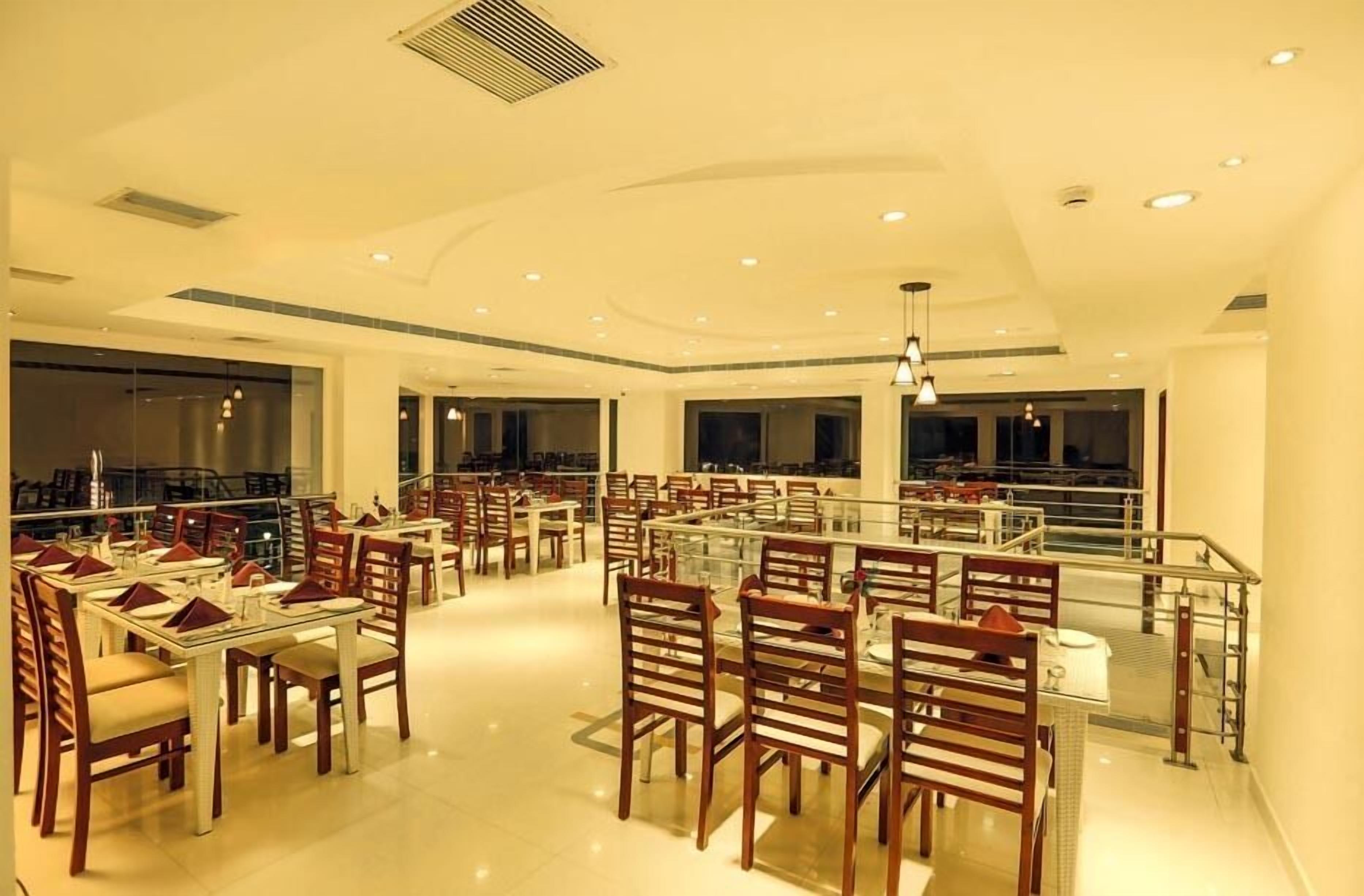 Un restaurante amplio con numerosas mesas y sillas, ventanas grandes y un diseño moderno del techo.