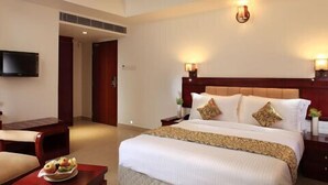 Una habitación de hotel con cama, mesitas de noche, televisor y una silla.