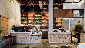 A modern bar area with a brick counter, stools, and a variety of bottles and plants. - Veriu Broadway (Ultimo)