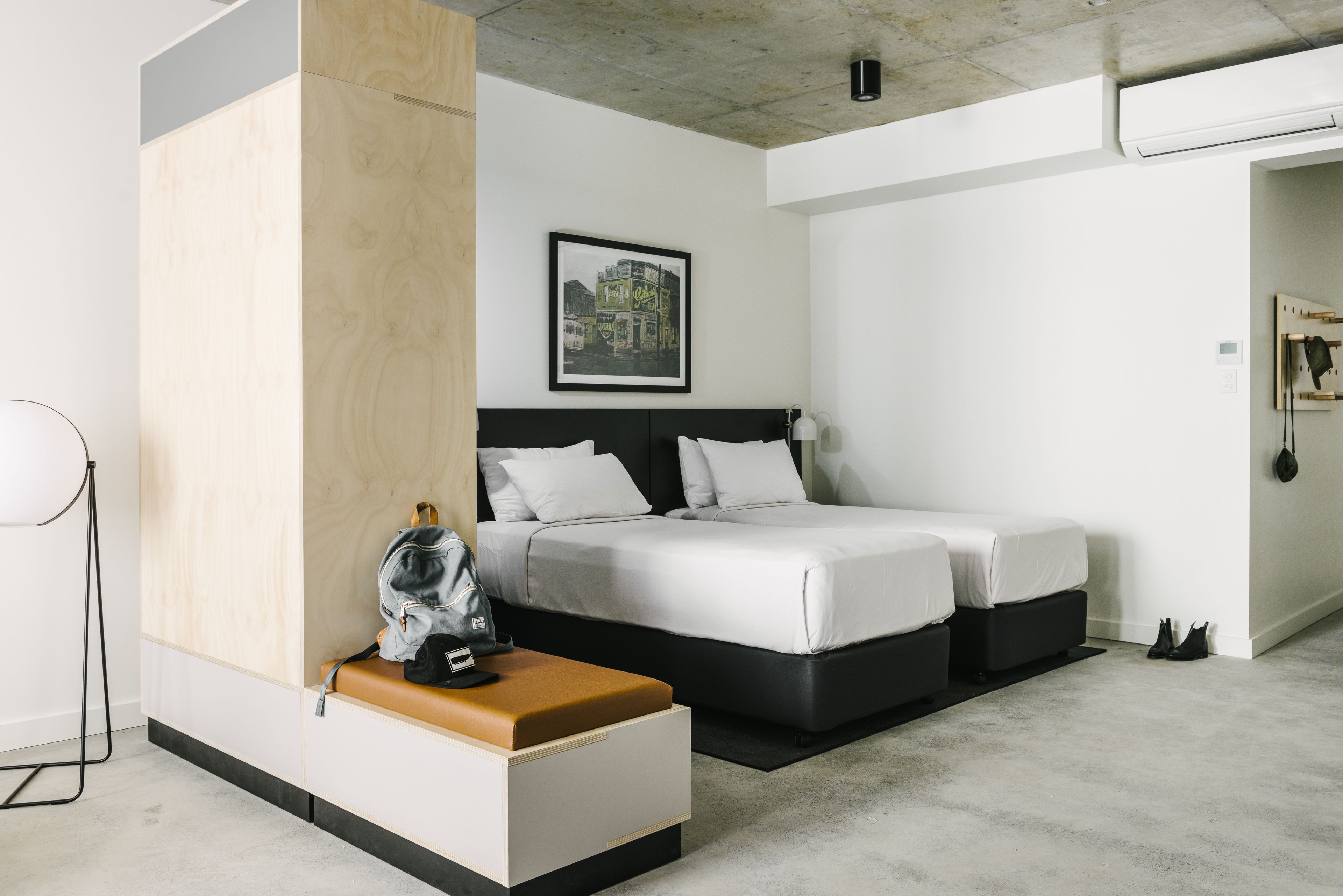 A modern hotel room with a large bed, a bedside table, a wardrobe, and a framed picture on the wall.