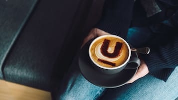 A person holding a cup of coffee with a latte art design.