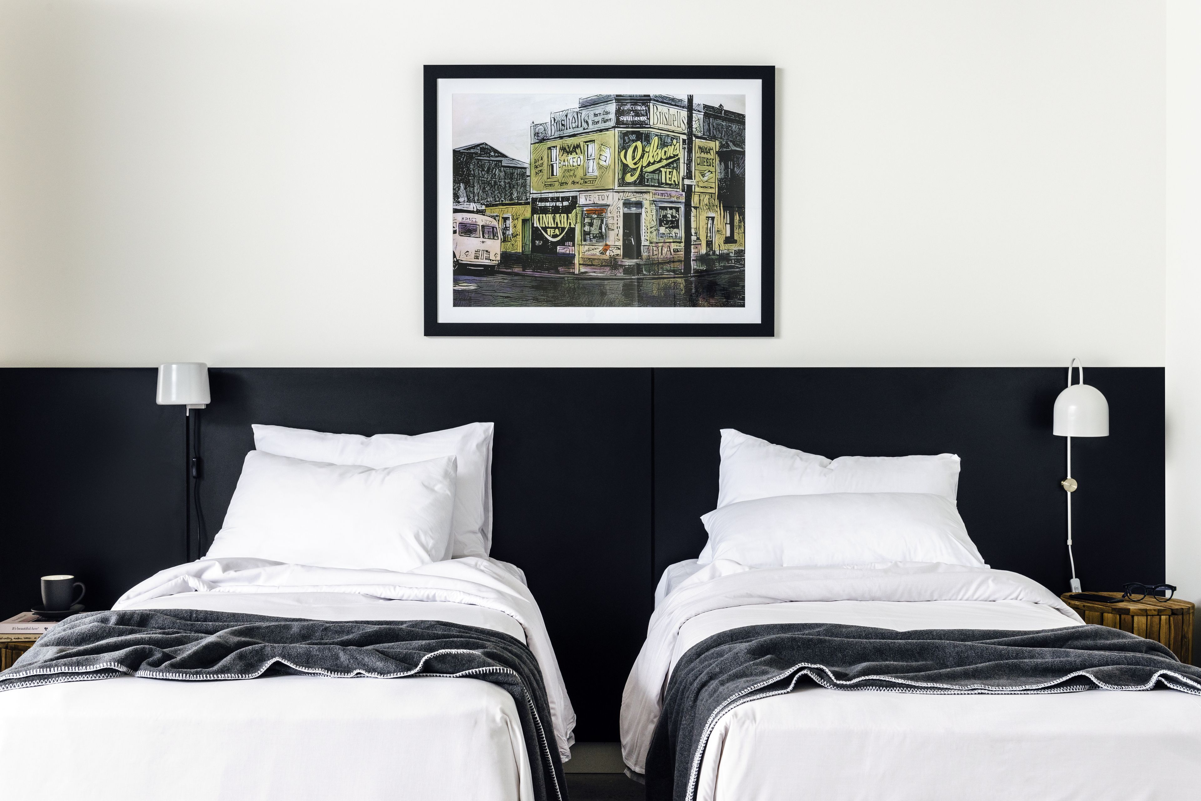 Une chambre d’hôtel avec deux lits, un tableau encadré au mur et une table de chevet avec une lampe.