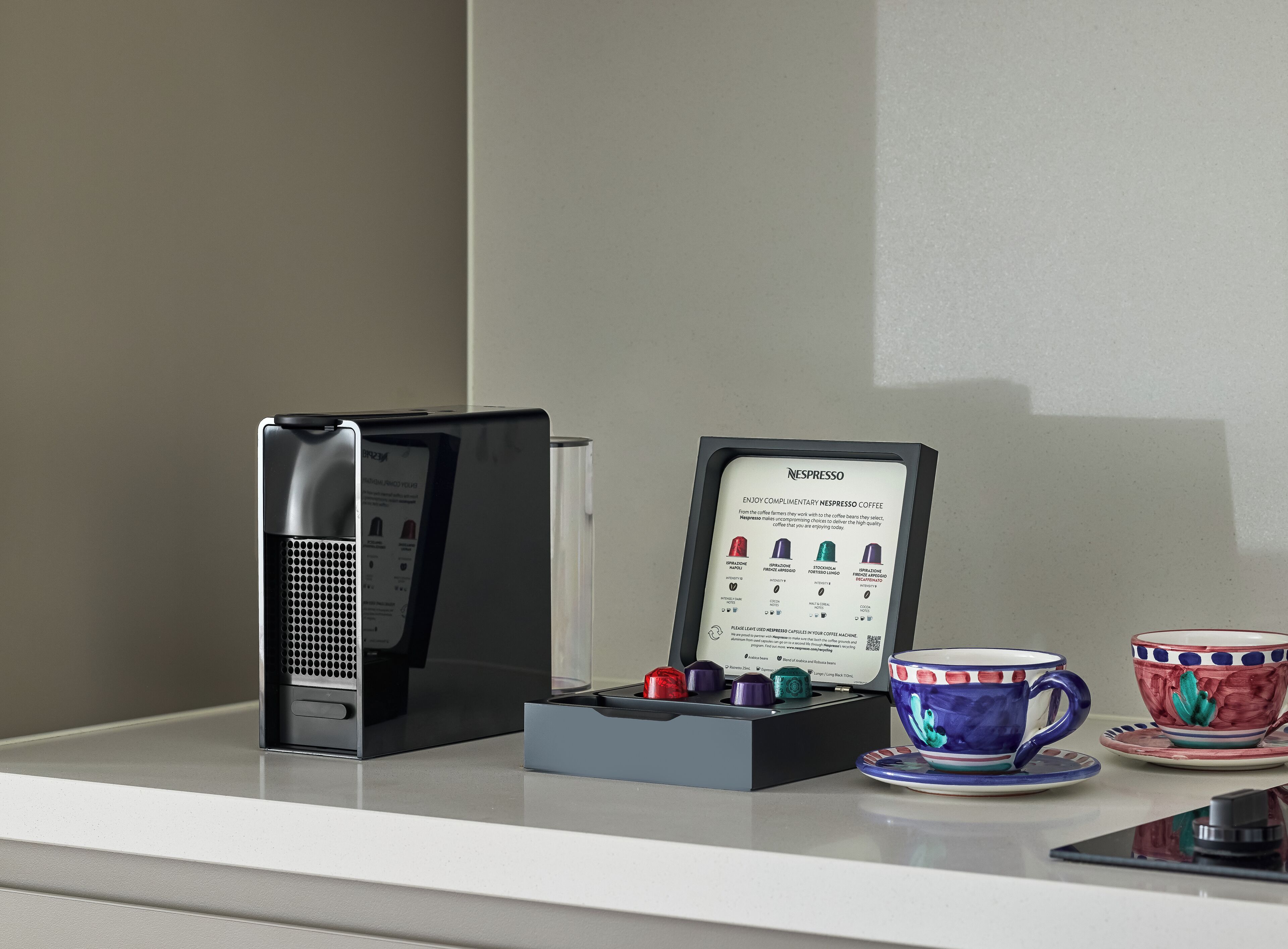 Máquina de café Nespresso e cápsulas em uma bancada.