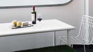 A modern room with a round window, a table with a bottle of wine, a glass, and some fruit. - Veriu Broadway (Ultimo)
