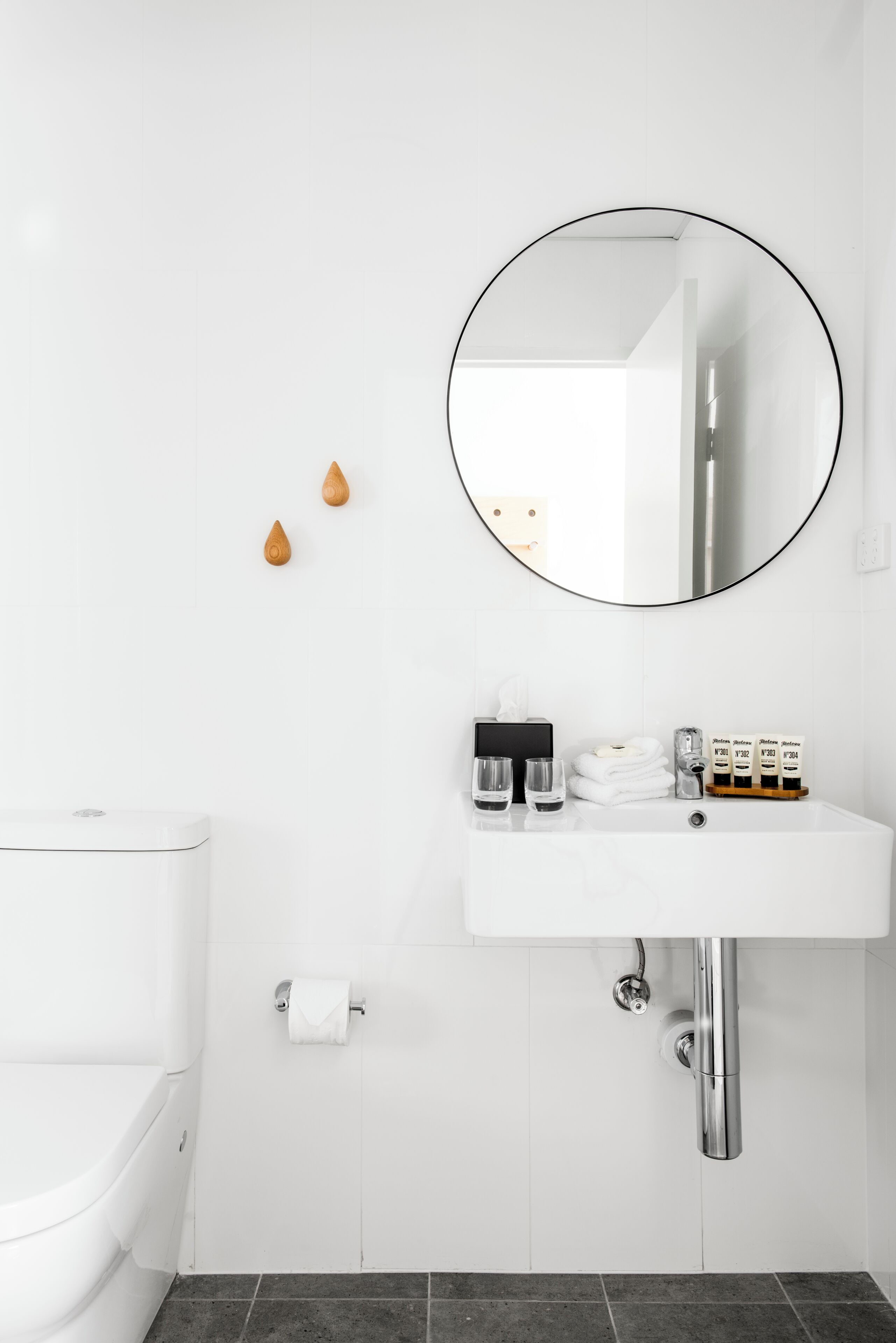 A modern bathroom with a white sink, a round mirror, and a toilet.