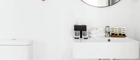 A modern bathroom with a white sink, a round mirror, and a toilet.