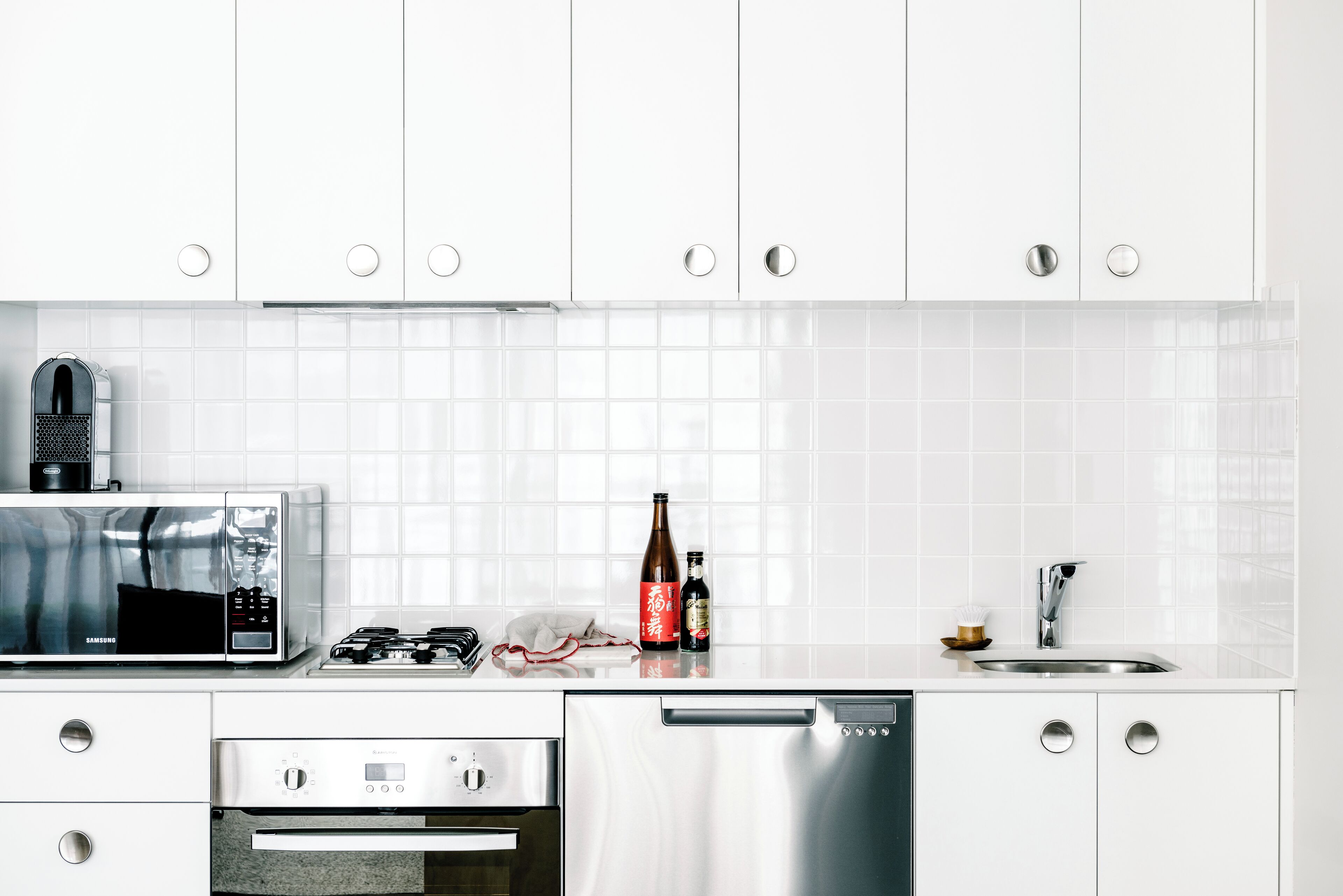 A modern kitchen with white cabinets, a microwave, a stove, an oven, and a dishwasher.