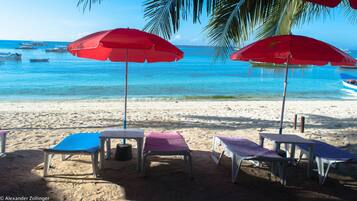 En la playa, playa de arena blanca, camastros y sombrillas