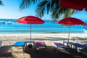 På stranden, hvit sand, solsenger og parasoller