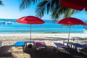 En la playa, arena blanca, sillas reclinables de playa, sombrillas