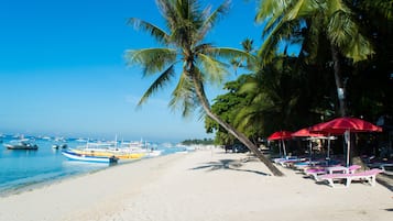 Aan het strand, wit zand, ligstoelen aan het strand, parasols