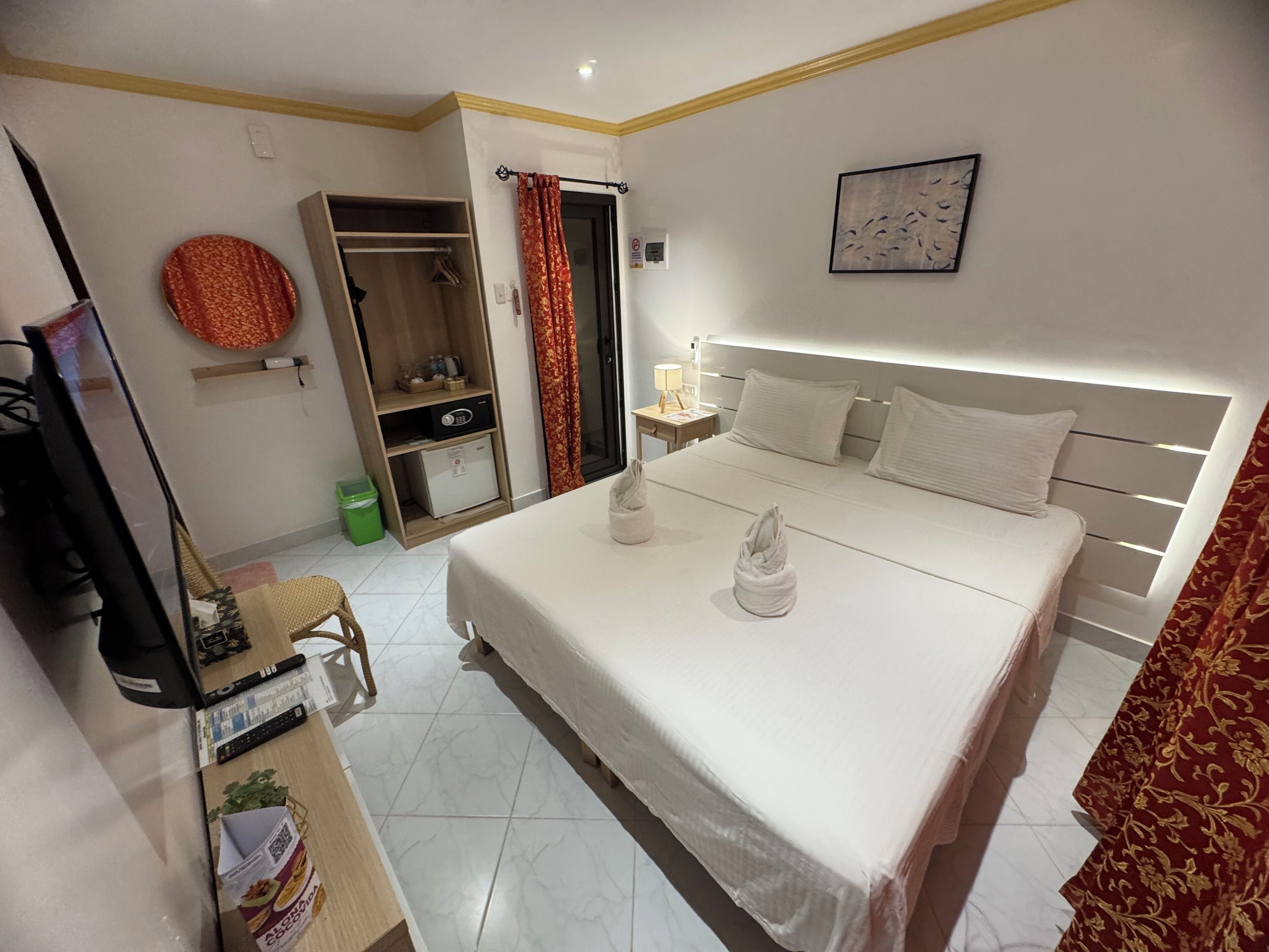 A hotel room with a bed, bedside table, lamp, and a wardrobe.