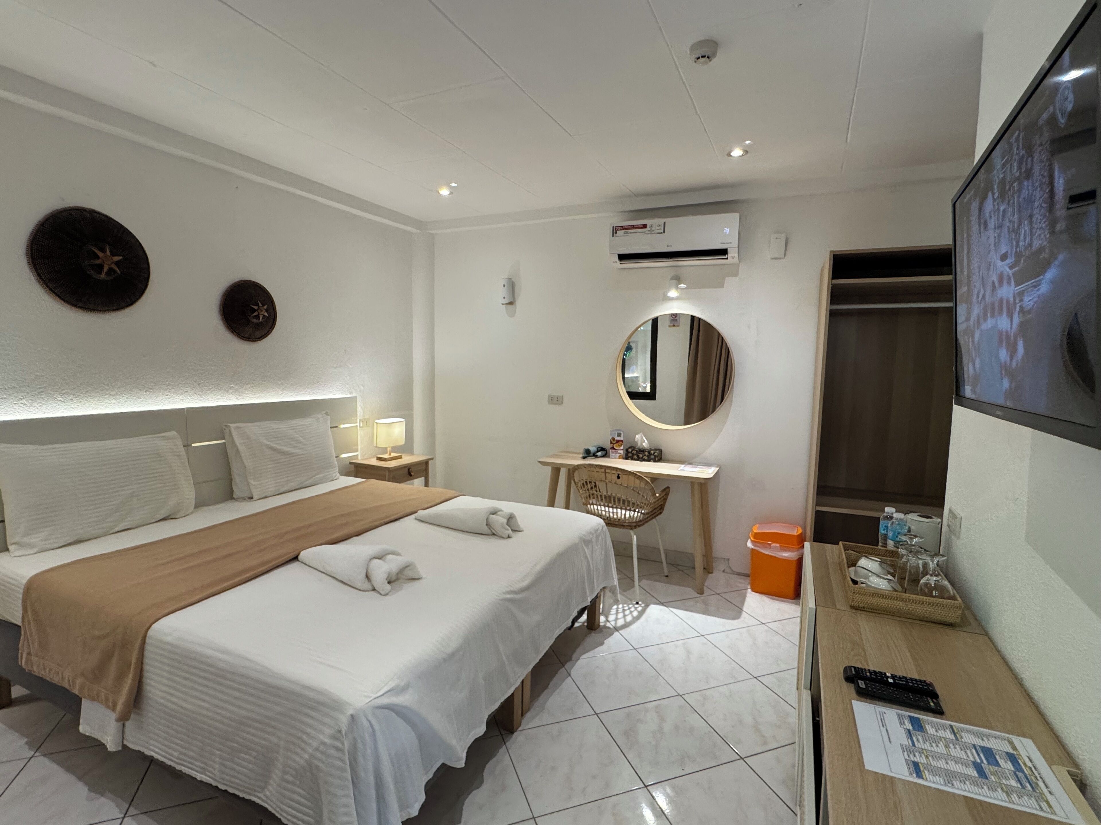 Une chambre d’hôtel comprenant un lit, une table de chevet, un bureau, une chaise, un miroir et un téléviseur.