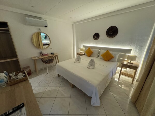 Una habitación de hotel con cama, mesitas de noche, escritorio, silla y espejo.