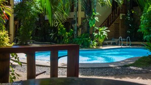 A pool surrounded by lush greenery, a wooden deck, and a staircase leading to a building. - Alona Vida Beach Resort (Panglao)
