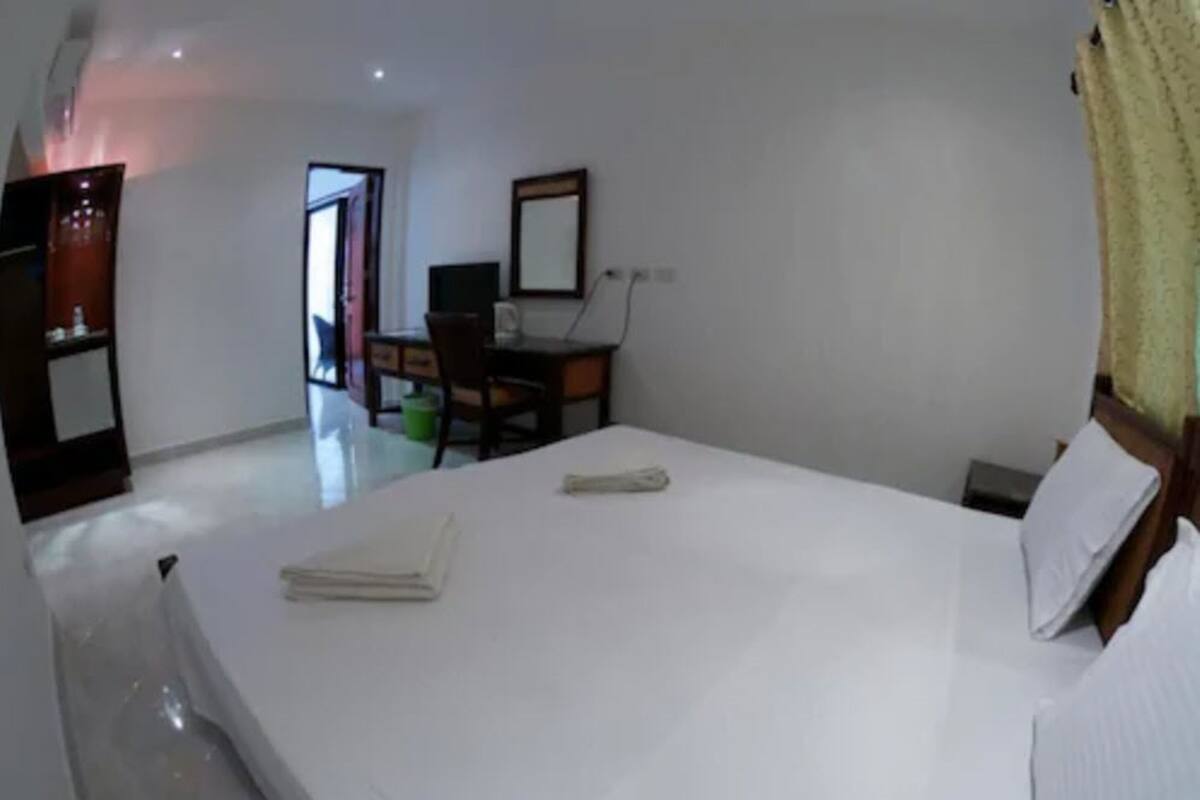 A hotel room with a large bed, a desk, and a chair.