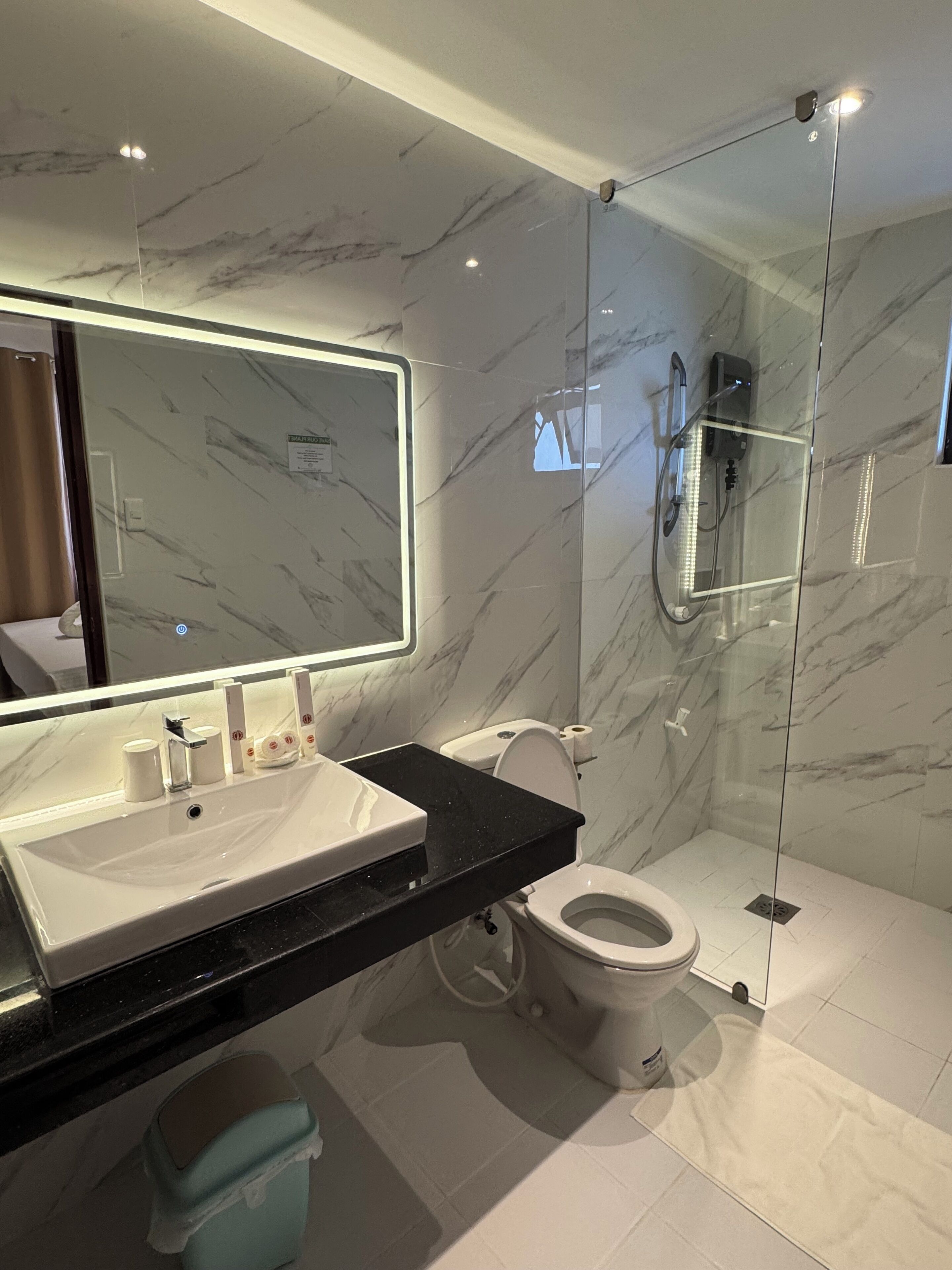 A modern bathroom with a marble vanity, a glass shower enclosure, and a toilet.