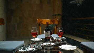 A dining table set with two wine glasses, a bottle of wine, and a small plant.