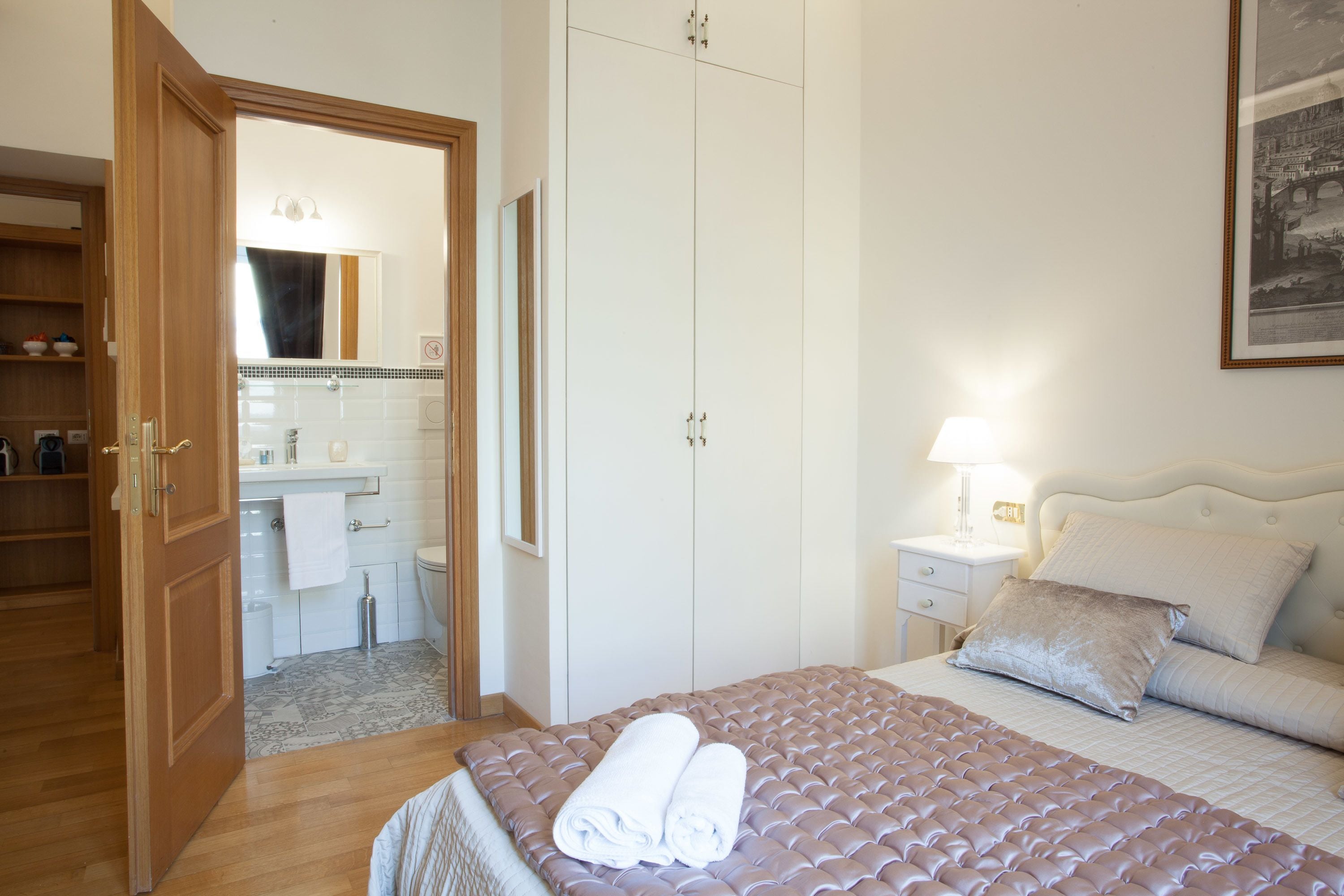 Une chambre à coucher comprenant un lit, une table de chevet, une lampe, un miroir et une armoire.