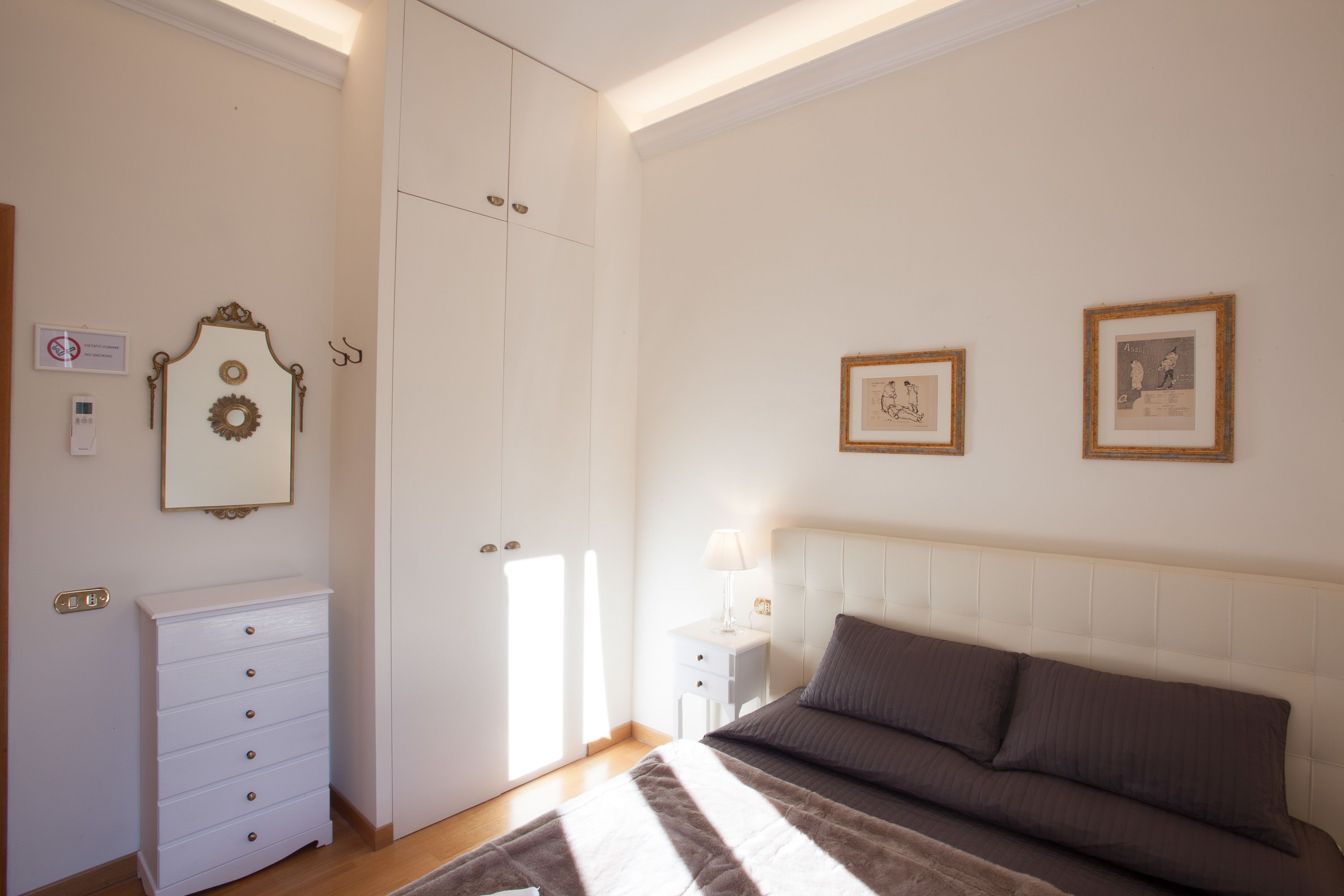 A bedroom with a bed, a dresser, a nightstand, and two framed pictures on the wall.