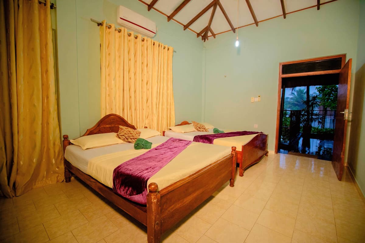 A room with two wooden beds, a curtain, and a door leading outside.