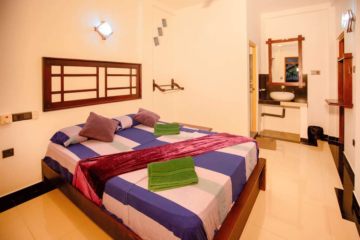 A neatly made bed with a striped bedspread, a headboard, and two pillows.