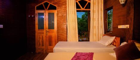 A wooden room with two beds, a window with curtains, and a wall-mounted light fixture.