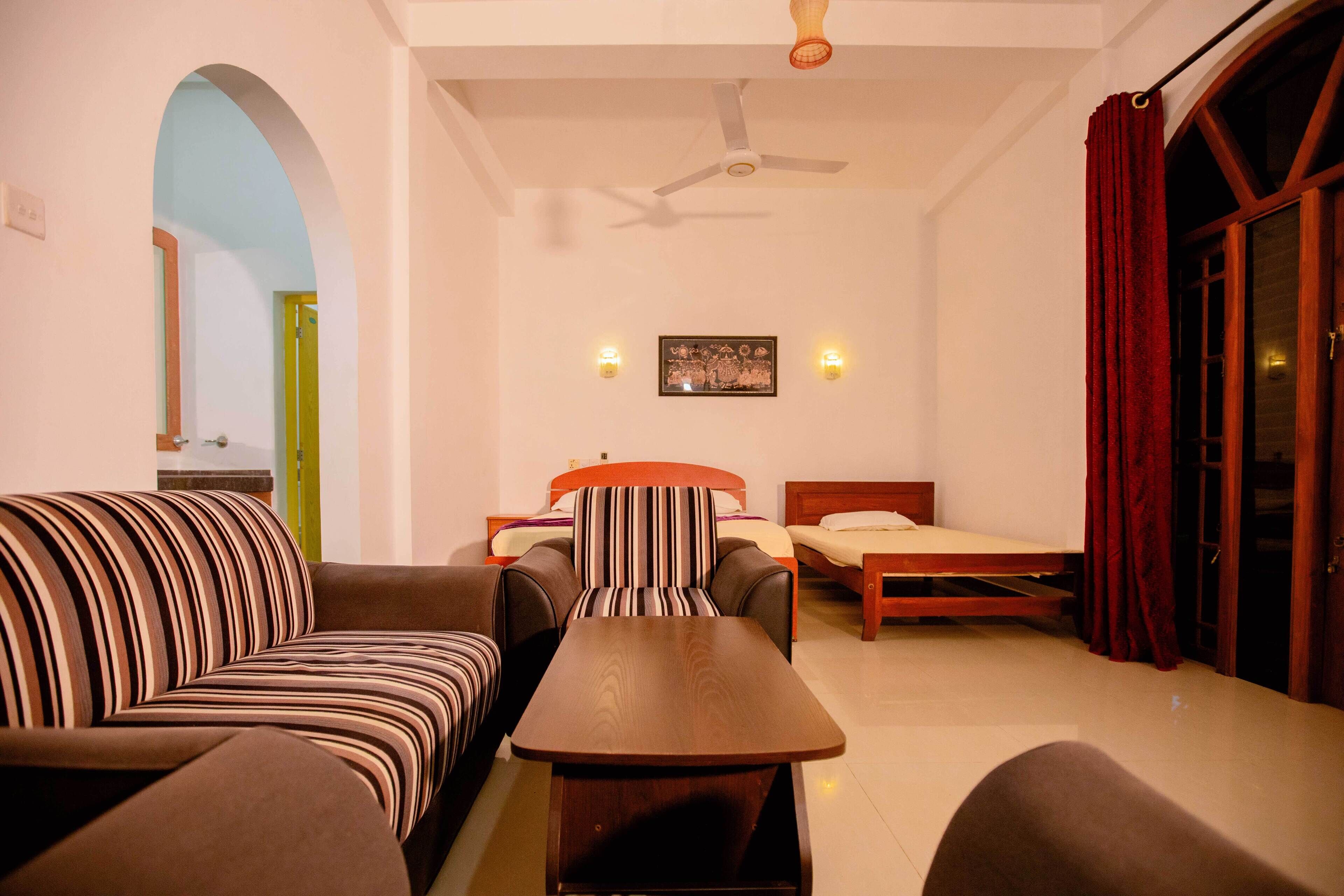 A room with a sofa, a bed, a table, and a ceiling fan.