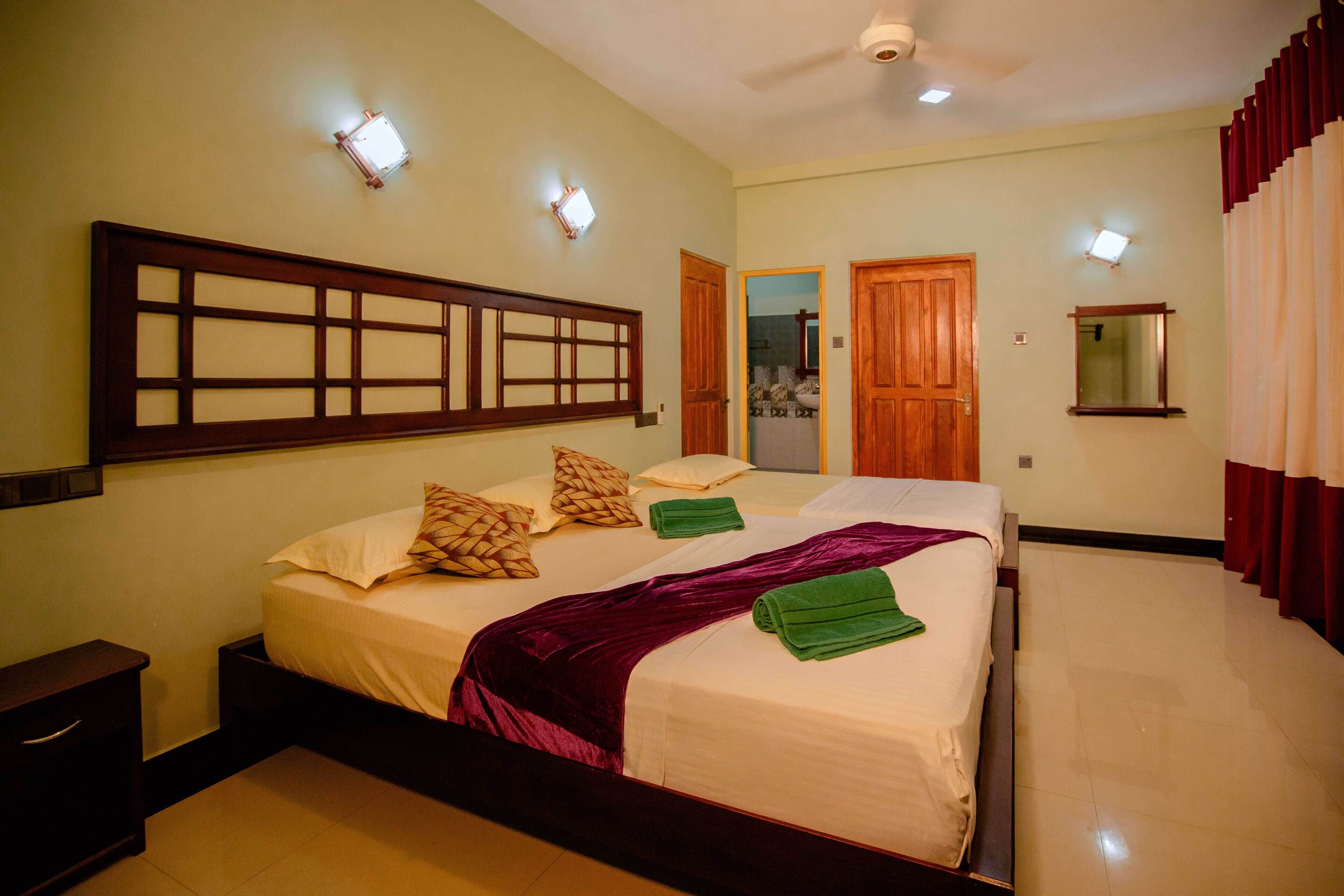 A hotel room with two beds, a wooden headboard, a nightstand, and a ceiling fan.