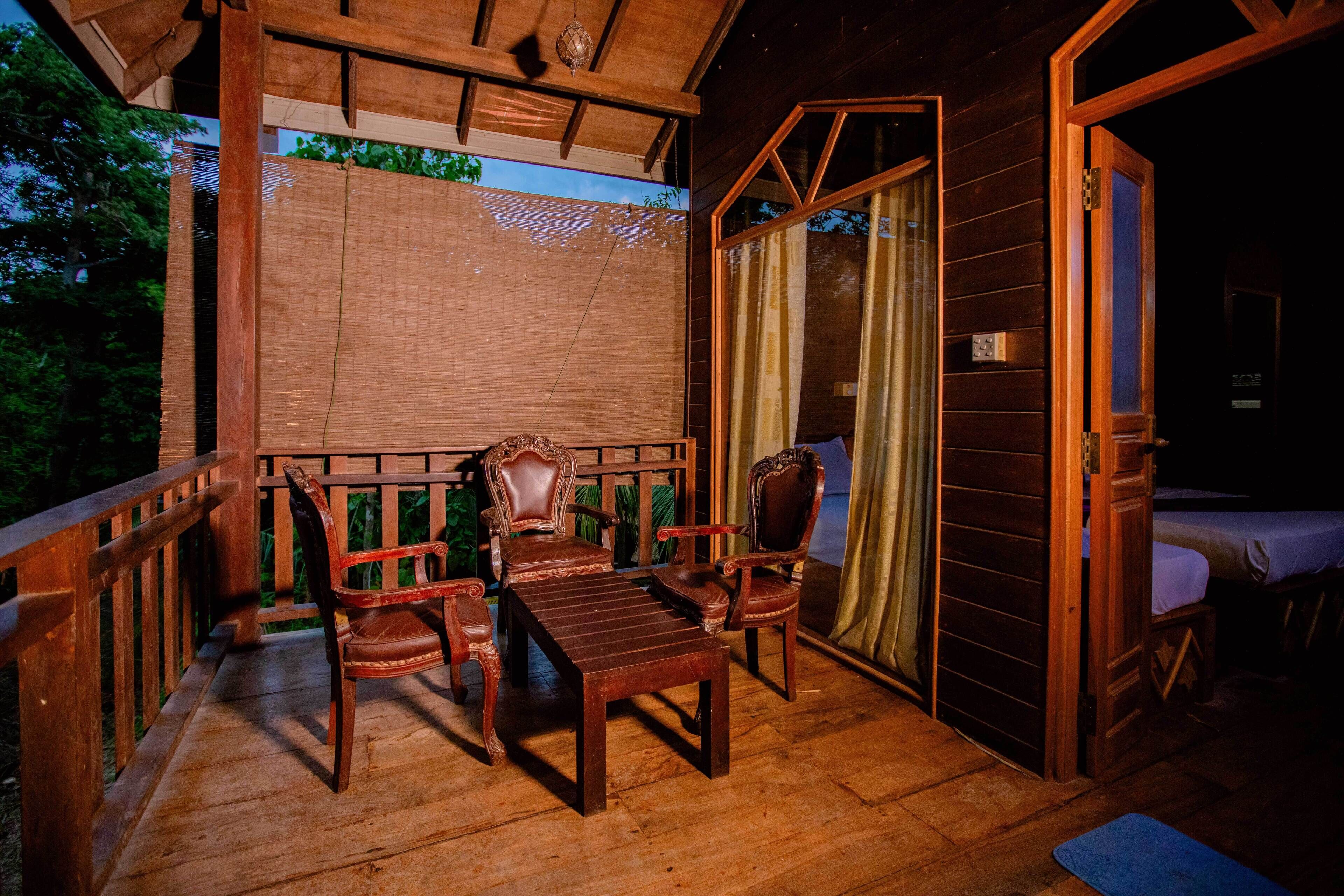 A wooden deck with a table and chairs, a wooden door, and a view of the outdoors.