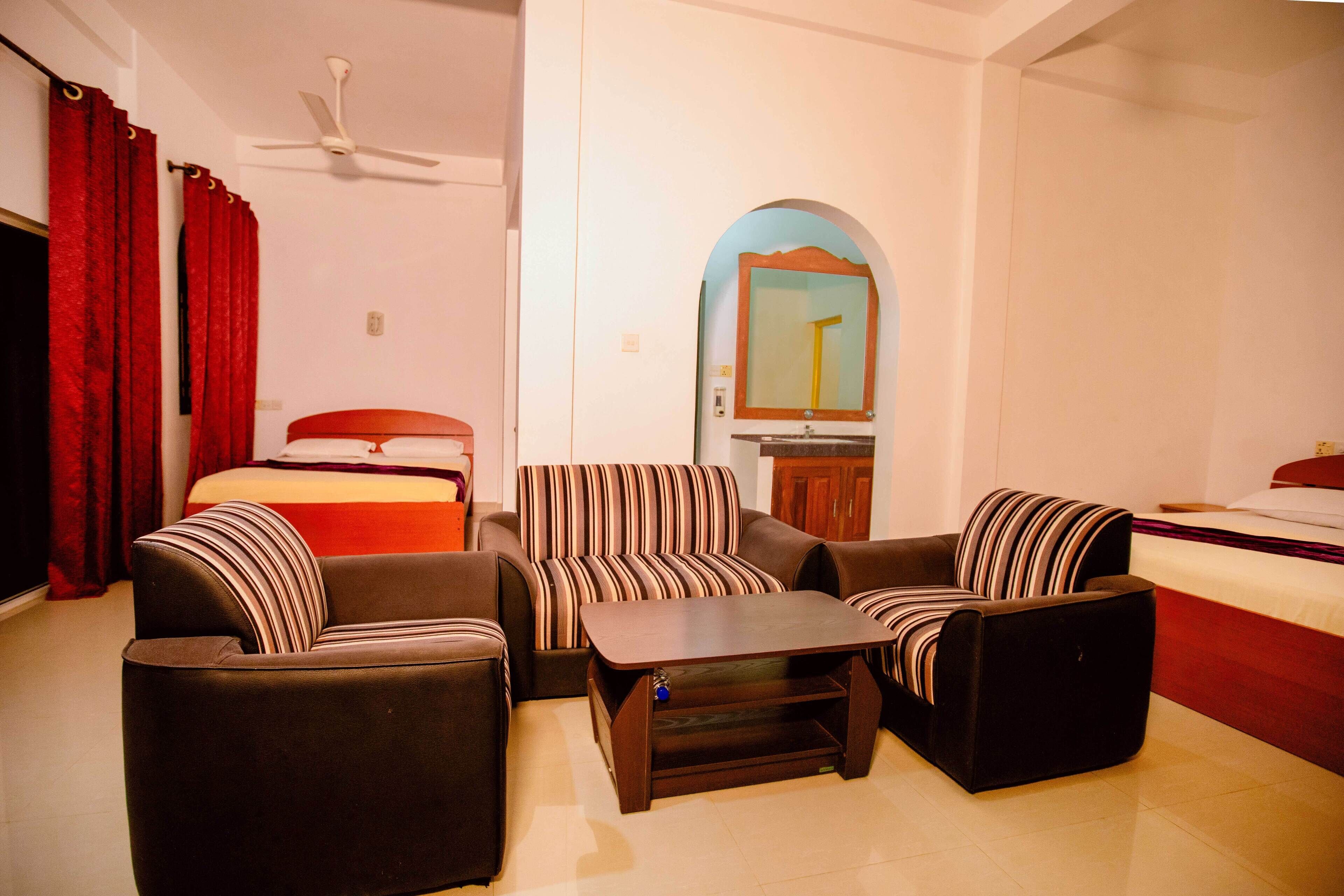 A hotel room with a bed, a sofa, a coffee table, and a mirror.