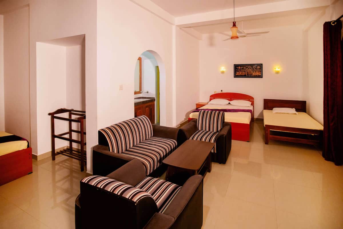 A hotel room with a sofa set, a bed, a small table, and a ceiling fan.