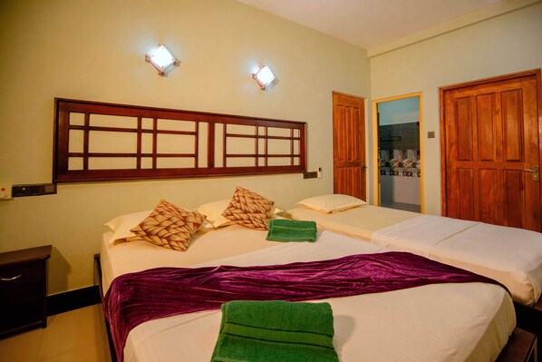 A hotel room with two beds, a wooden headboard, and a green towel on the bed.