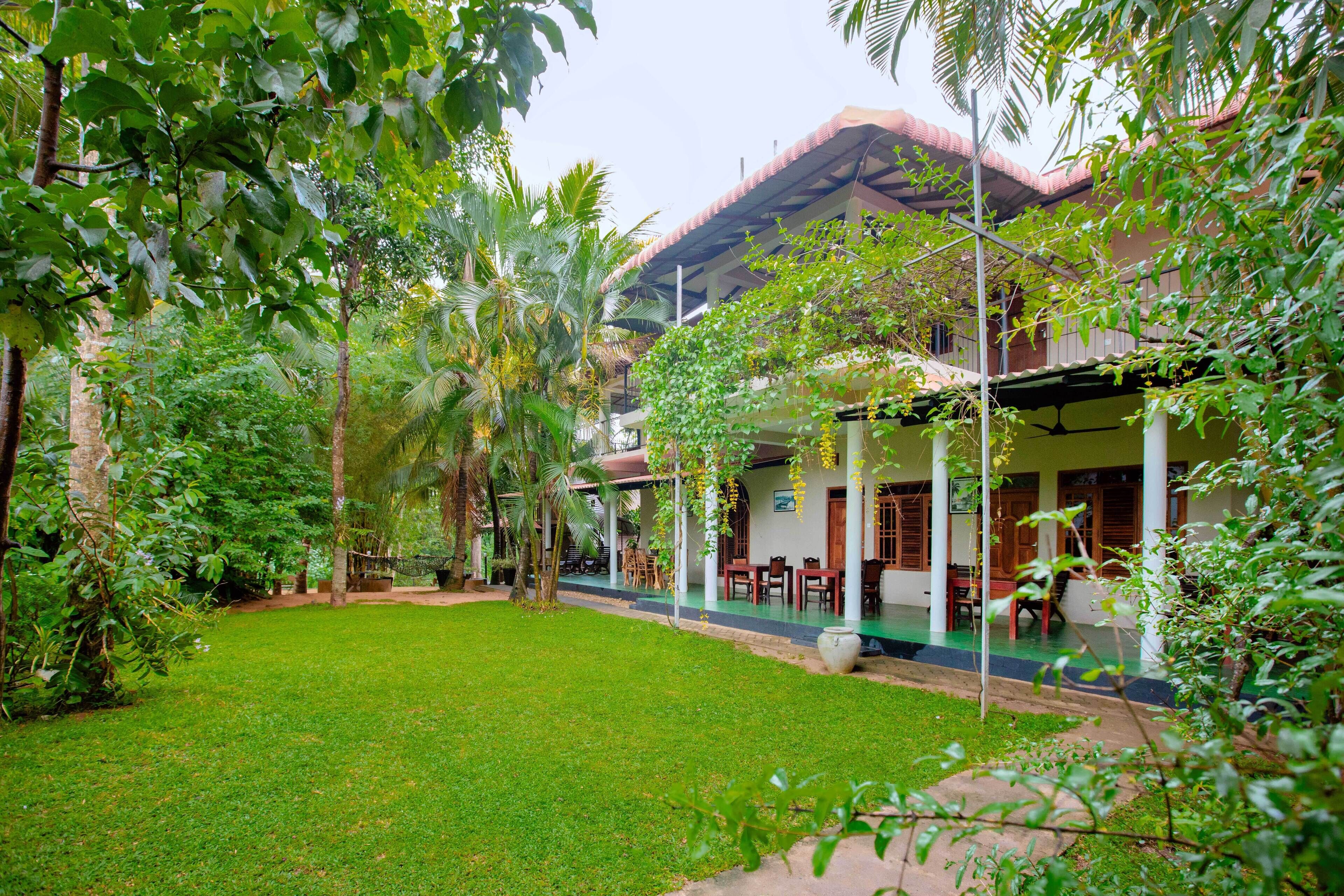 A traditional house with a covered porch, surrounded by lush greenery and a well-maintained lawn.