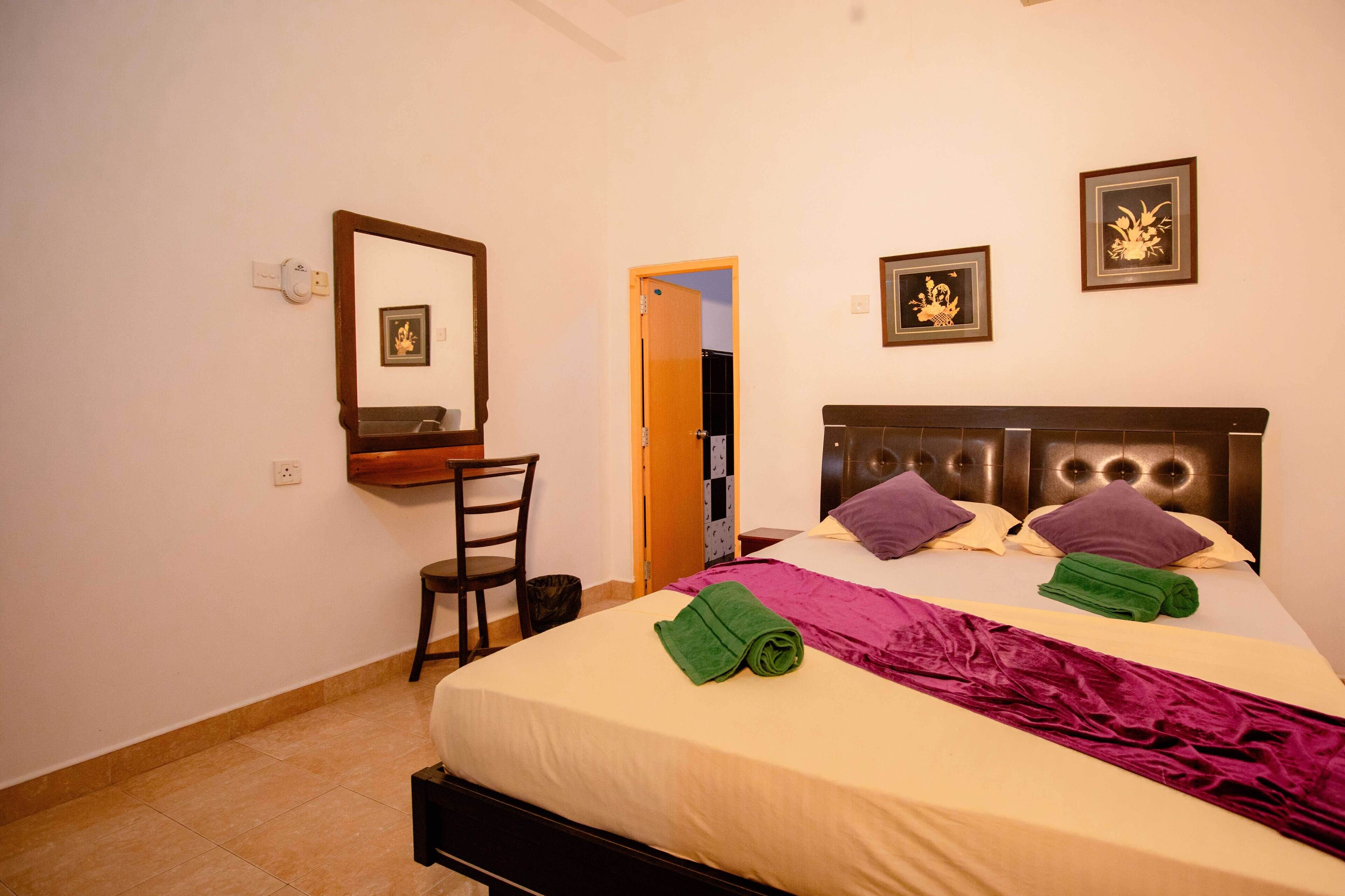 Un dormitorio con cama, una silla, un escritorio y una puerta.